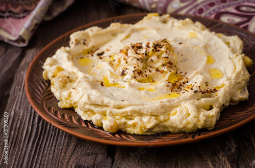 Plate of creamy hummus on wooden table.Ramadan food. Selective focus. Toned image