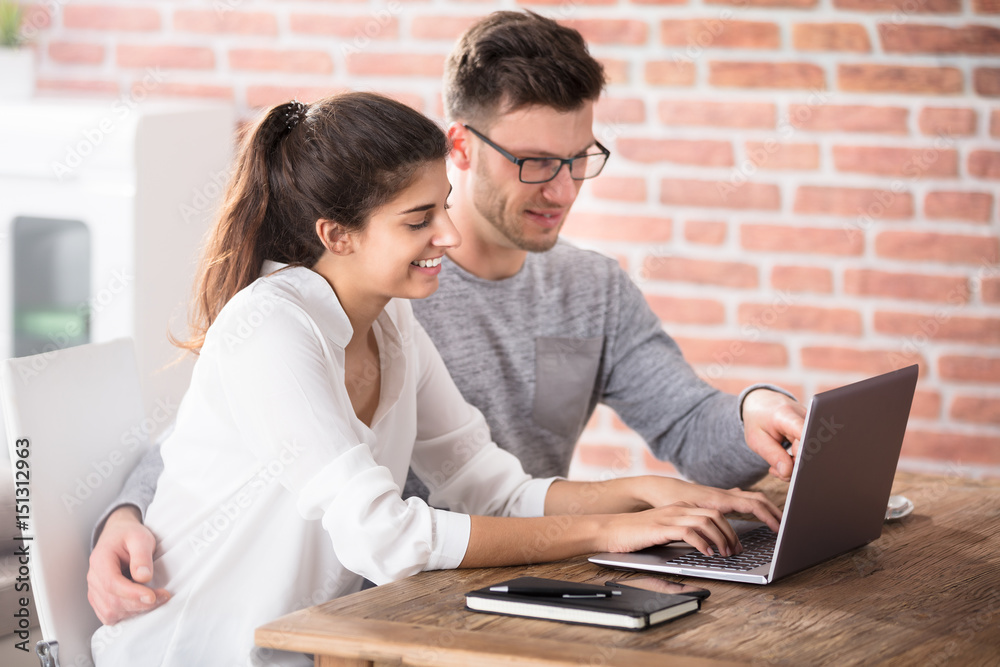 Happy Couple Looking At Laptop On Table Happy Couple Looking At Laptop On Table