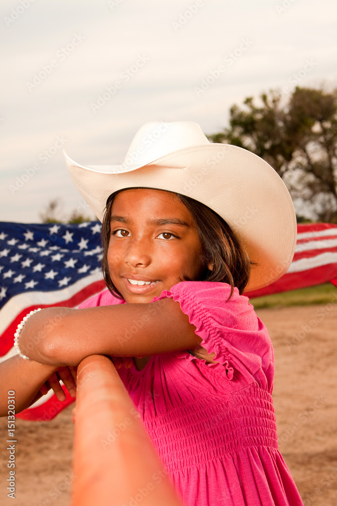 Hispanic little girl wearing a hat with an American flag.