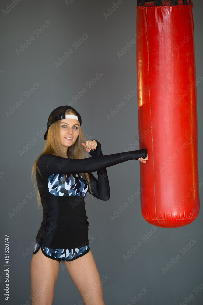 Beautiful slender young girl beats a boxing pear in the gym