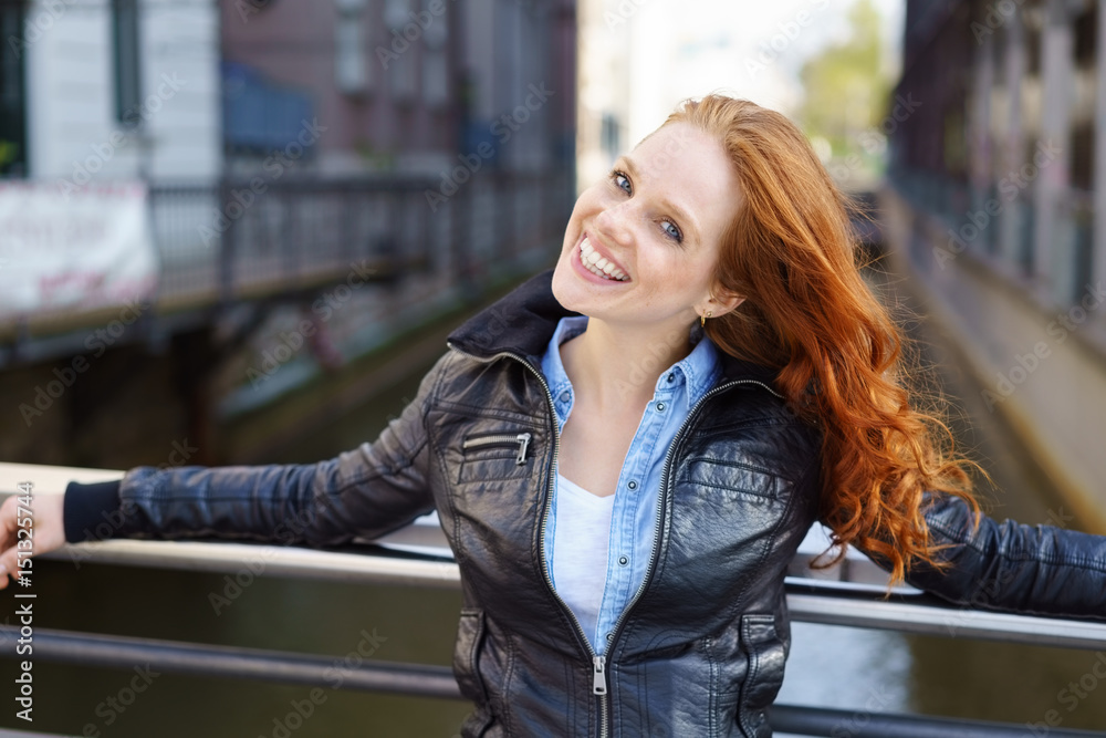 frau mit einer schwarzen lederjacke steht auf einer brücke in der stadt frau mit einer schwarzen lederjacke steht auf einer brücke in der stadt