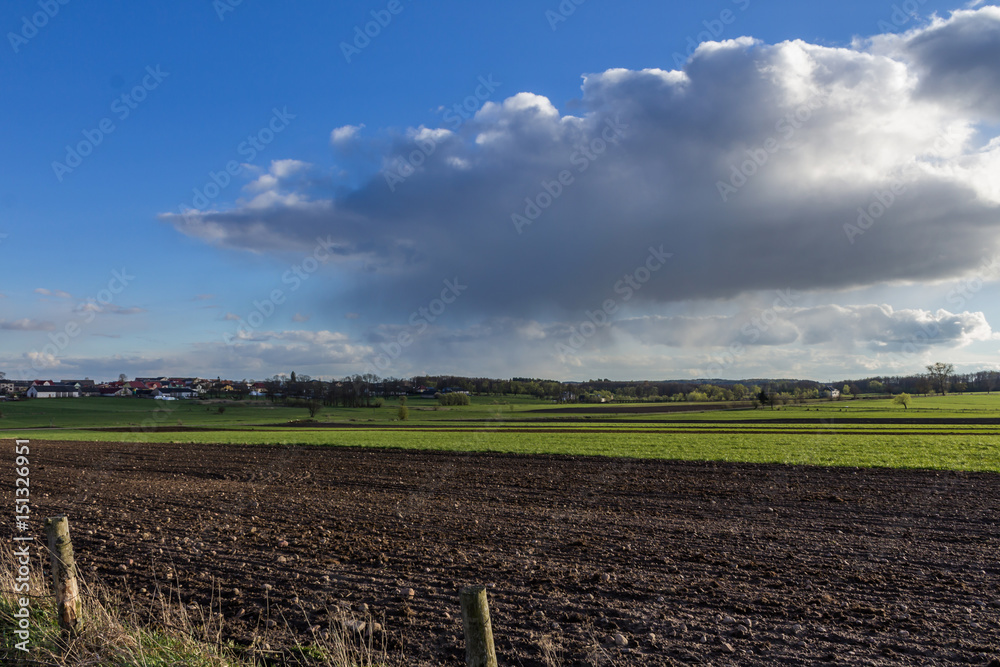 Plowed field,  meadow and the village on the hill. Houses, dairy farms, barns. Early Spring on Podlasie, Eastern Poland.