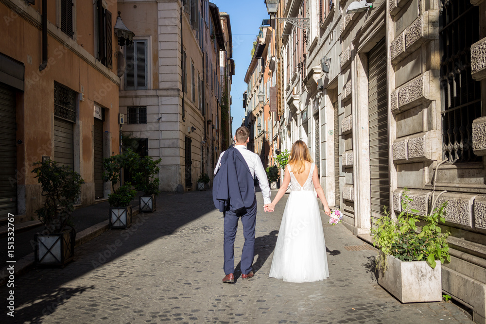 Obraz premium Young beautiful bride and groom on the wedding walk through the streets of old Rome, Italy.