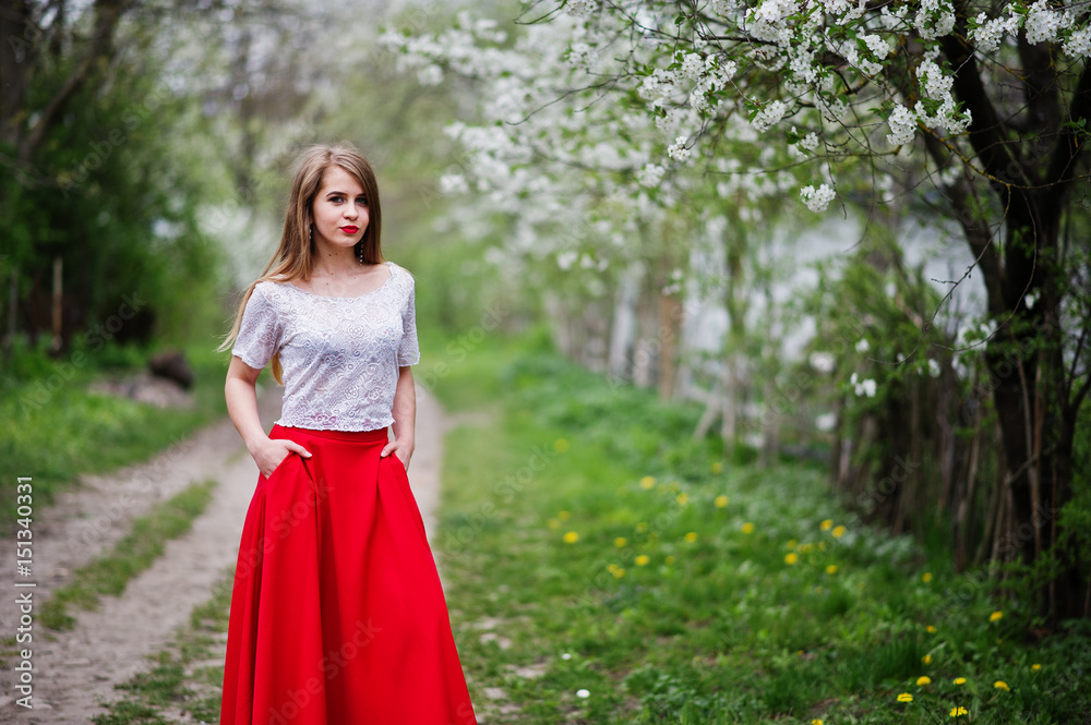 Portrait of beautiful girl with red lips at spring blossom garden, wear on red dress and white blouse.