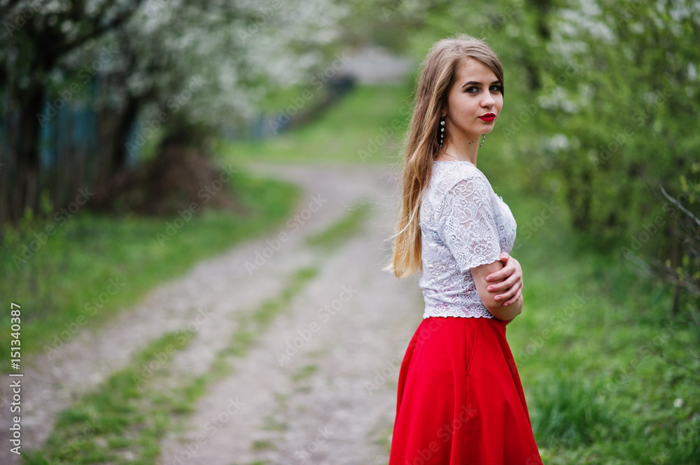 Portrait of beautiful girl with red lips at spring blossom garden, wear on red dress and white blouse. Portrait of beautiful girl with red lips at spring blossom garden, wear on red dress and white blouse.