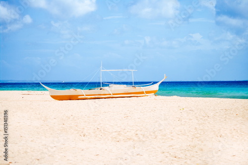 Tropical white sand beach, and fishing boat parked in the sand. Exotic island paradise