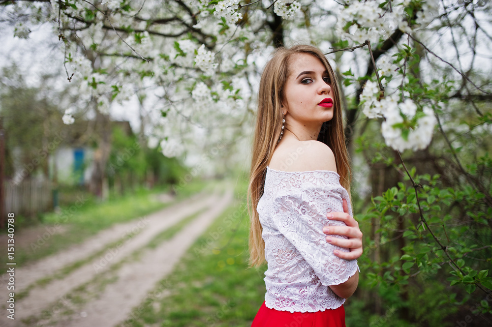 Portrait of beautiful girl with red lips at spring blossom garden, wear on red dress and white blouse. Portrait of beautiful girl with red lips at spring blossom garden, wear on red dress and white blouse.