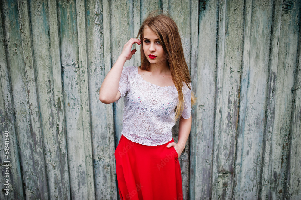 Fototapeta premium Portrait of beautiful girl with red lips against wooden background, wear on red dress and white blouse.