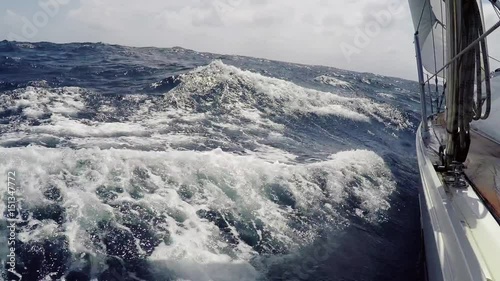 Yachting on on the sea in summer day. Yacht, boat goes through foamy blue waves at high speed, pov. Endless blue sea, in the background the horizon line