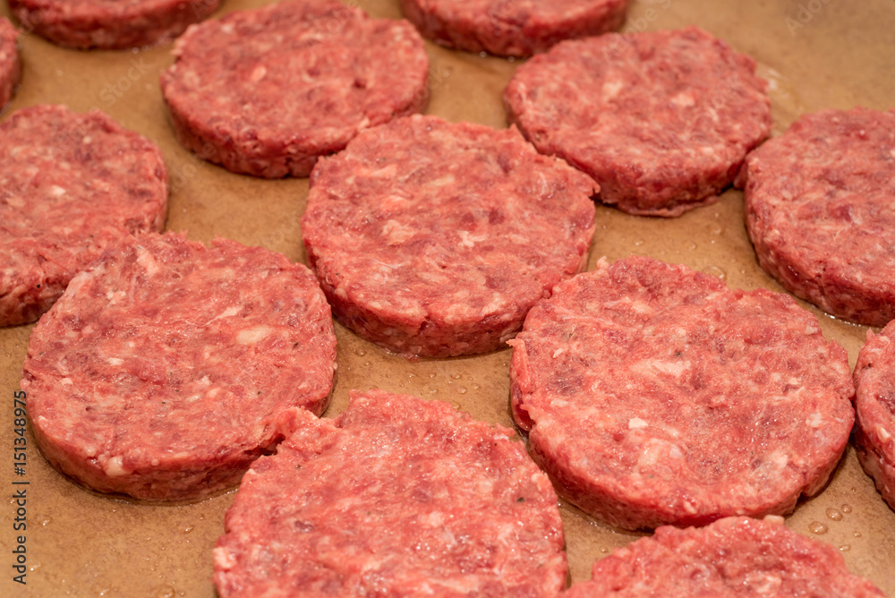 Fresh raw beef burger patties on paper background