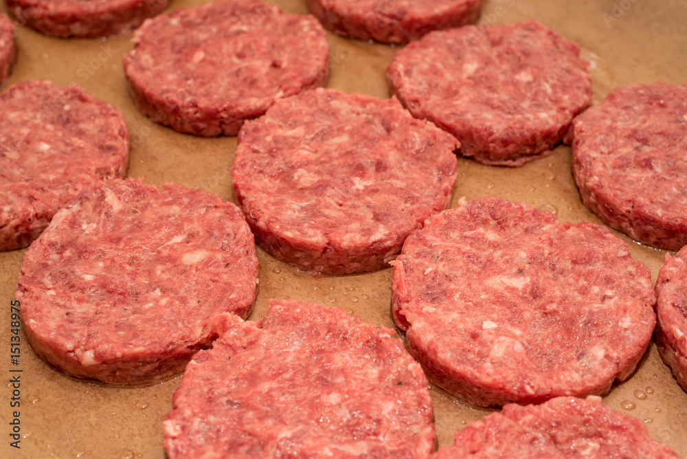 Fresh raw beef burger patties on paper background Fresh raw beef burger patties on paper background