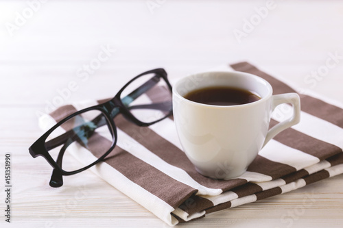 Cup of coffee, glasses  on white wooden table
