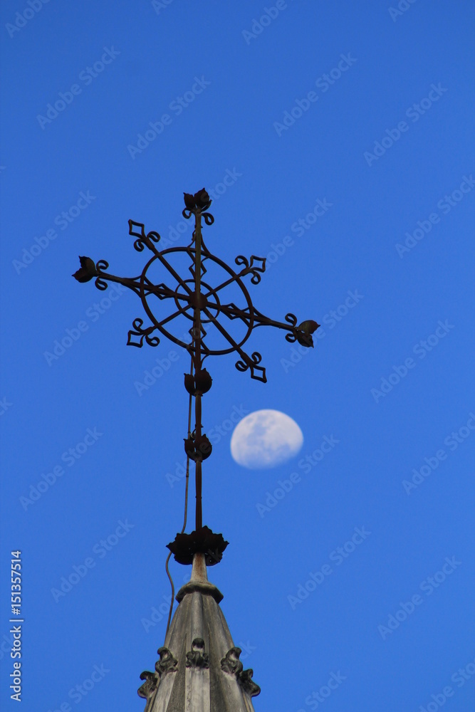 Cruz de hierro forjado en firmamento con luna.