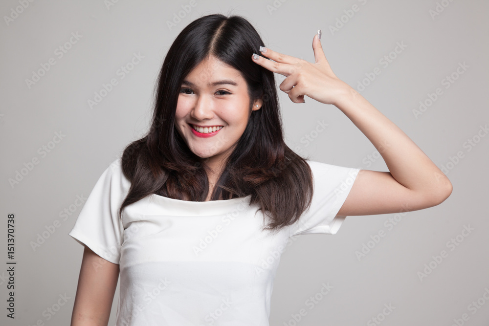 Beautiful young Asian woman holding fingers in gun gesture.