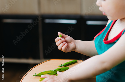 Bilde på lerret Mixed race girl shelling pea pod at dining table