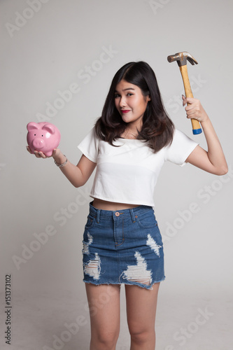 Asian woman with pig coin bank and hammer.