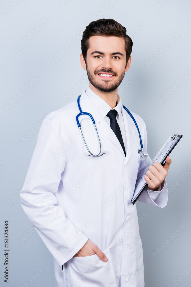 Vertical portrait of successful happy smiling doctor in uniform holding clipboard Vertical portrait of successful happy smiling doctor in uniform holding clipboard