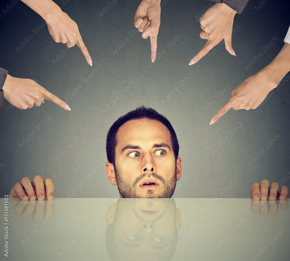 Scared man young employee hiding under the table being accused by many  people who point fingers at him Stock Photo | Adobe Stock