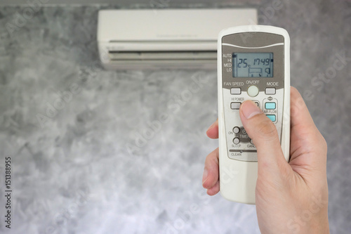 Wallpaper Mural Hand holding remote in front of air conditioner. Torontodigital.ca