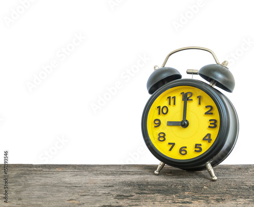 Closeup black and yellow alarm clock for decorate in 9 o'clock on old brown wood desk isolated on white background with copy space