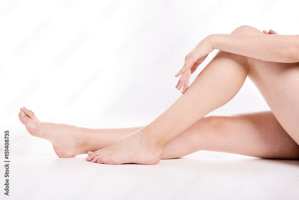 Woman holding on leg. Beautiful fit long female legs, isolated on white background. Spa woman touching her slim legs. Woman holding on leg. Beautiful fit long female legs, isolated on white background. Spa woman touching her slim legs.