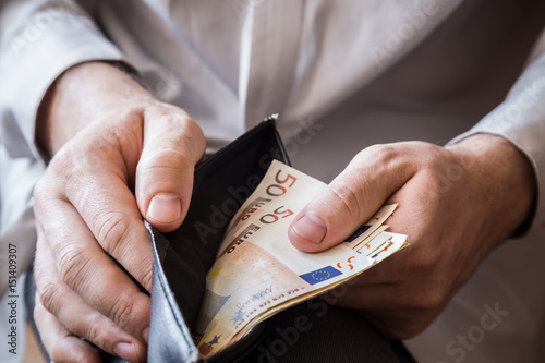 Man's hand holding a black wallet with euro money. photo