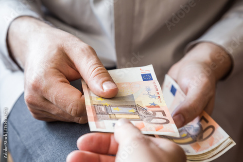 Man's hand giving a money. Dealing with euro banknotes.