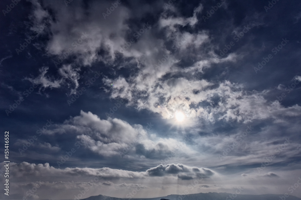 Sky, sunlight. Background. Blue sky with clouds, from behind the clouds the sun peeps. Sky, sunlight. Background. Blue sky with clouds, from behind the clouds the sun peeps.