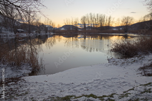 A small lake at dusk in winter, with snow and ice