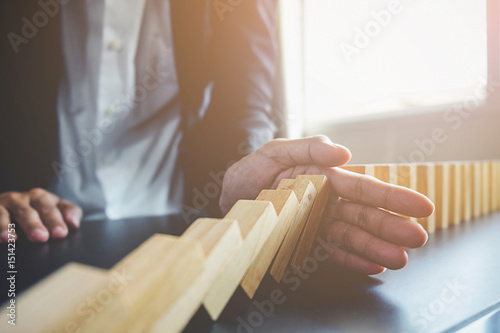 Problem Solving,Close up view on hand of business woman stopping falling blocks on table for concept about taking responsibility. photo