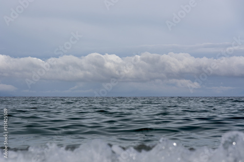 Seascape with clouds and mountains at horizon line, Aegean sea, Greece; spring day