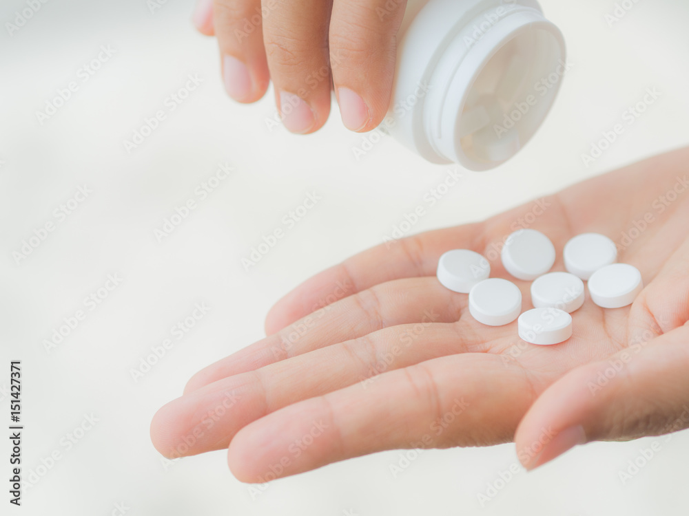 A young woman pours out medicine into her hand A young woman pours out medicine into her hand