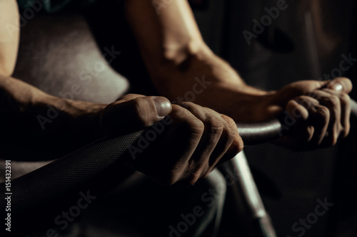 Hands of an athlete close-up  which does an exercise with a barbell. gym. biceps