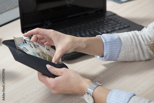 Counting the bribe, a black envelope in the hands of a business woman