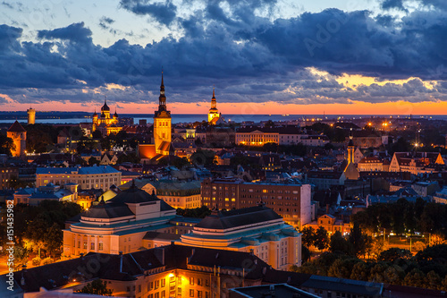 TALLINN, ESTONIA - JULY, 30, 2016: Orange sunset over old town. Cathedrals towers and modern buildings aerial view.