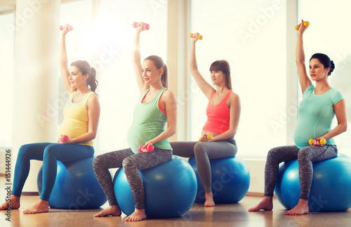 happy pregnant women exercising on fitball in gym