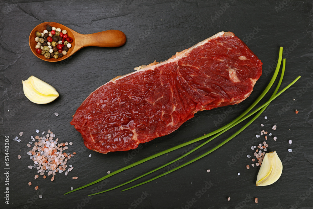 Raw beef steak meat cut and spices on black board