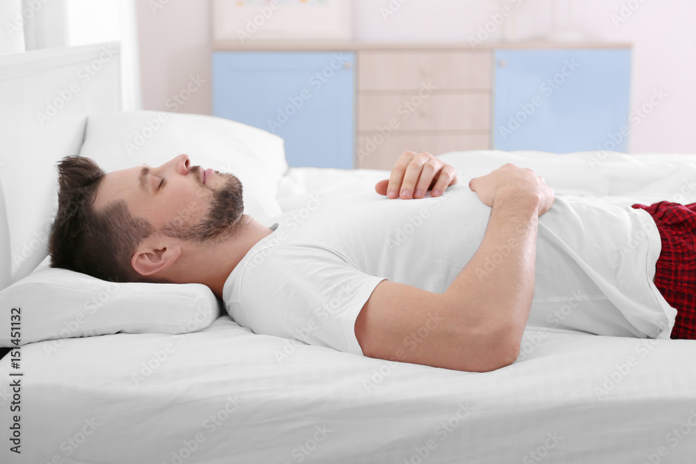Young man lying on bed with orthopedic pillow at home Young man lying on bed with orthopedic pillow at home
