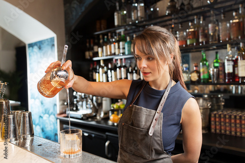 barmaid with glass and jug preparing cocktail