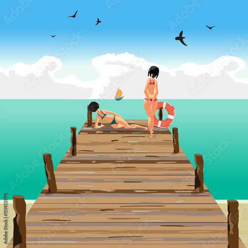 Two young women on a wooden pier on the beach looking at a sail