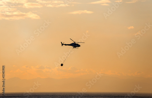 The helicopter collects water from the sea to extinguish a fire © faber121