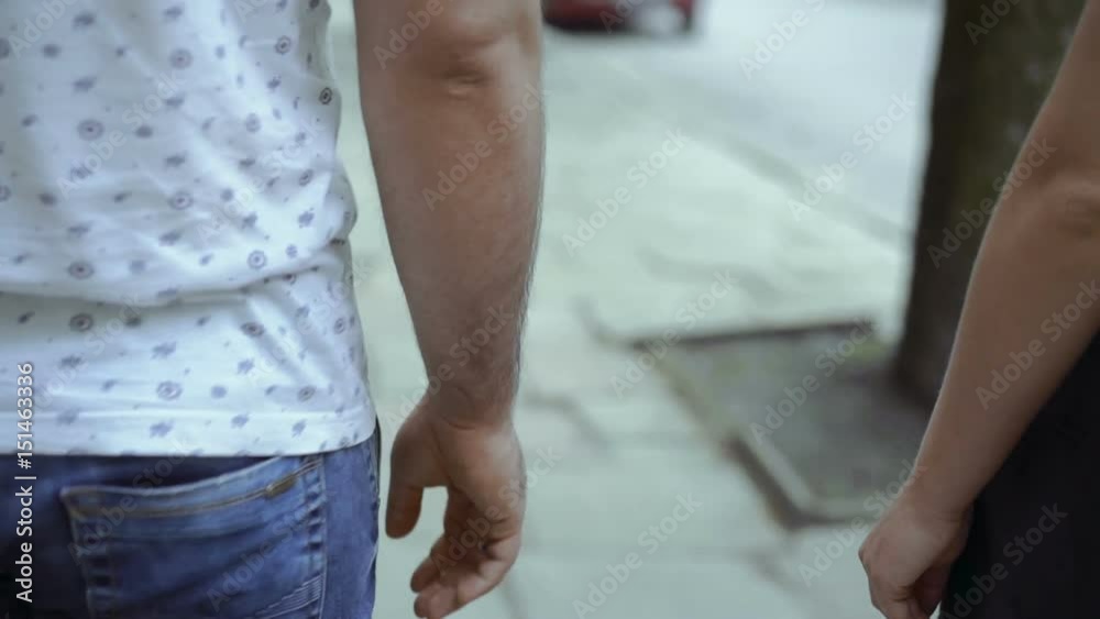 Back look of two lovers walking on the street and joins hands. Slowly Back look of two lovers walking on the street and joins hands. Slowly