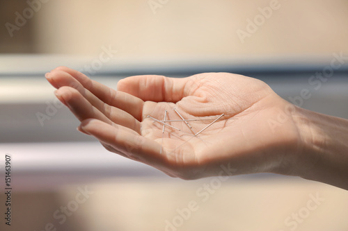 Female hand with needles for acupuncture on blurred background