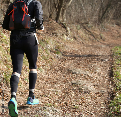 runner from behind during racing on the mountain trail in winter
