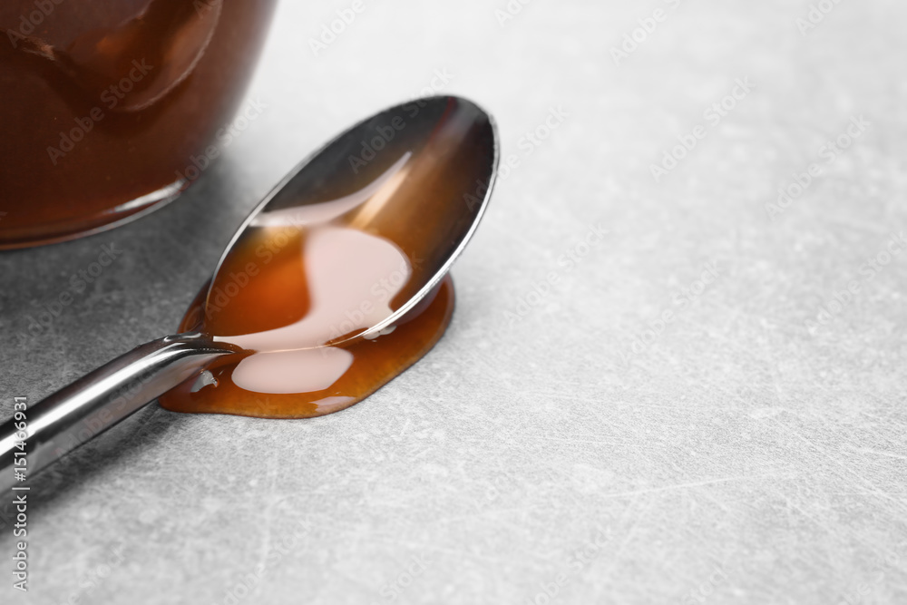 Spoon with tasty caramel sauce on light background, closeup Spoon with tasty caramel sauce on light background, closeup