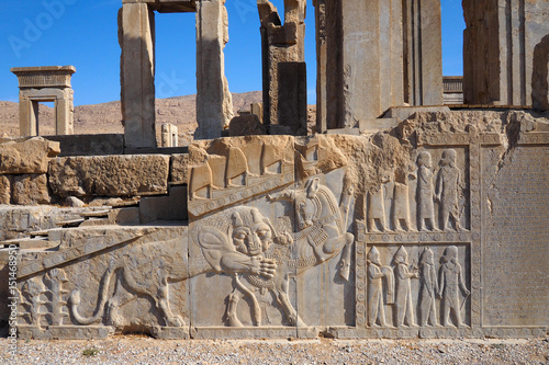 Ruins of Apadana and Tachara Palace behind stairway with bas relief carvings in Persepolis UNESCO World Heritage Site against cloudy blue sky in Shiraz city of Iran.