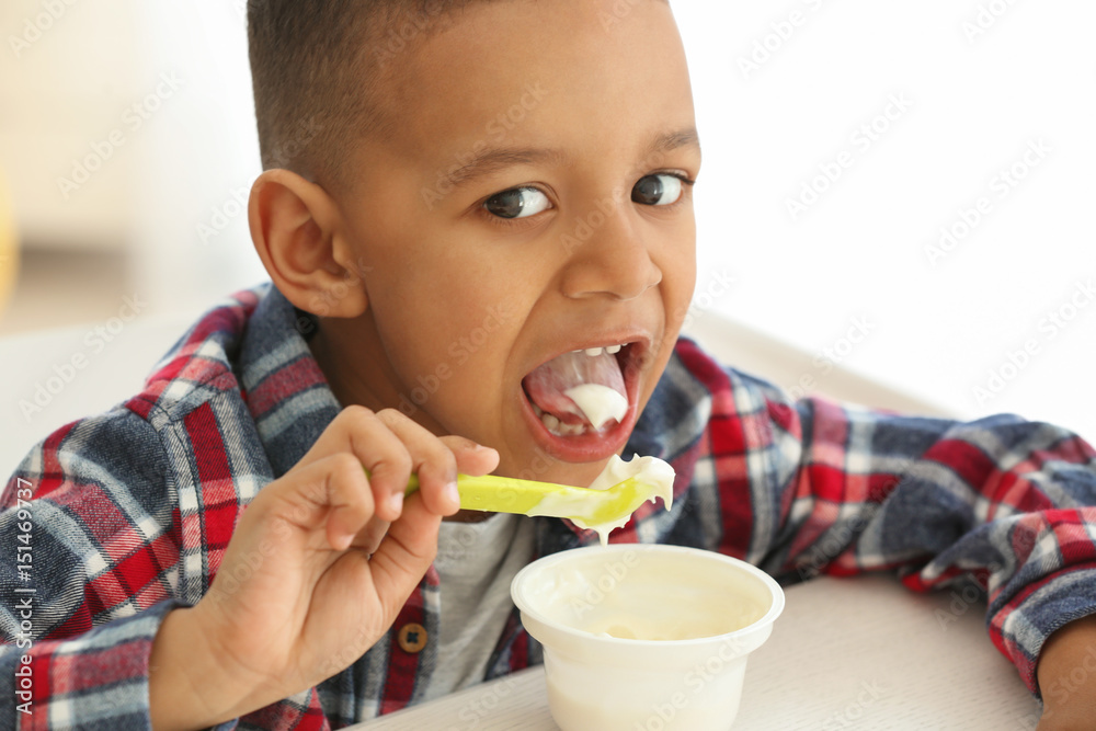 Cute African American boy eating yogurt at home, closeup Cute African American boy eating yogurt at home, closeup