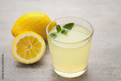 Glass of delicious lemon juice on table