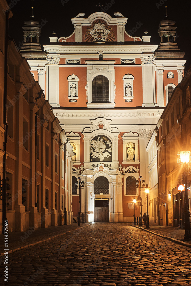 Baroque facade of the parish church in Poznan by night .