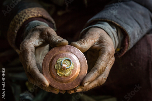 Fotografia An old craftsman is holding in his hand a cup, traditional Tibetan copper handicraft product in his workshop in Chilling village in the Indian Himalaya
